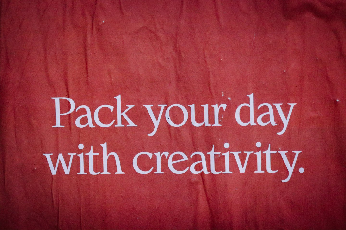 White text on a textured red background reads Pack your day with creativity.