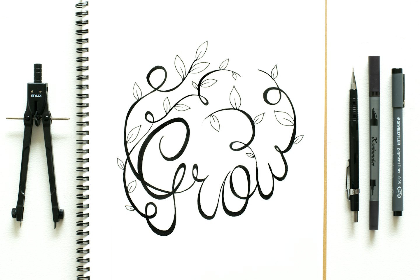 Hand-lettered illustration of 'Grow' with vines in a notebook.